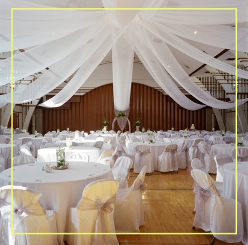 White chair covers and table linens give this wedding reception a very sleek