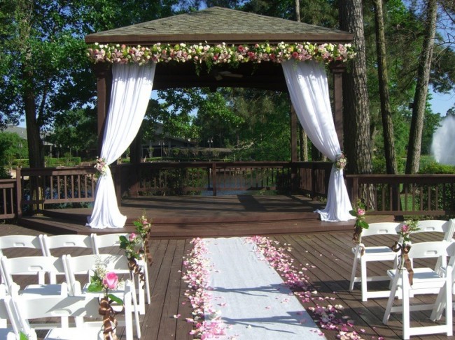 The gazebo decor for her wedding ceremony is accented in white 