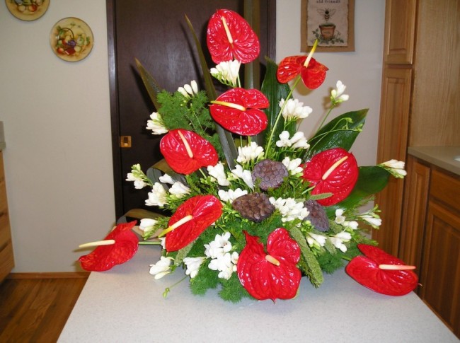 Anthuriums and freesia accented with lotus pods for buffet centerpiece
