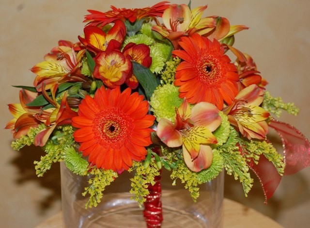 This compact style wedding bouquet contains a vibrant mixture of orange 