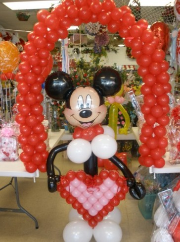 This themed balloon bouquet for a wedding shows Mickey Mouse holding a heart 