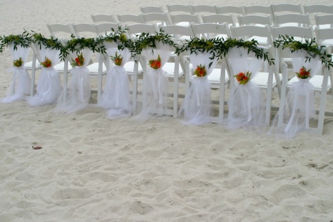 White chairs with white tulle accents were outlined with greenery