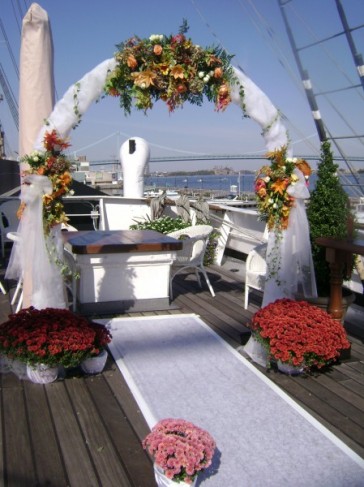 A tulle covered wedding arch was decorated with fallcolored flowers
