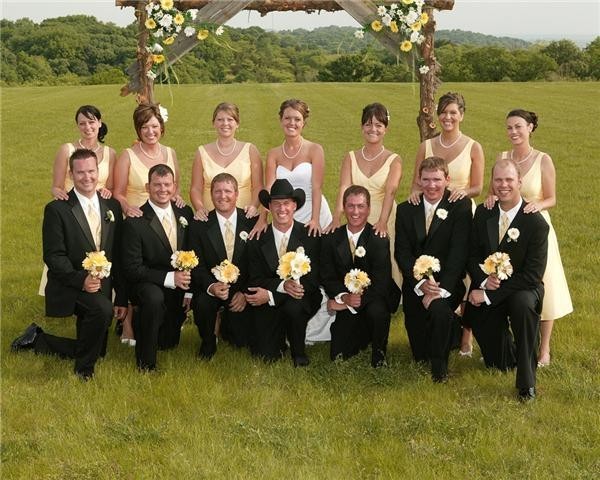  the wedding party is together near the wedding arch perched in a country 