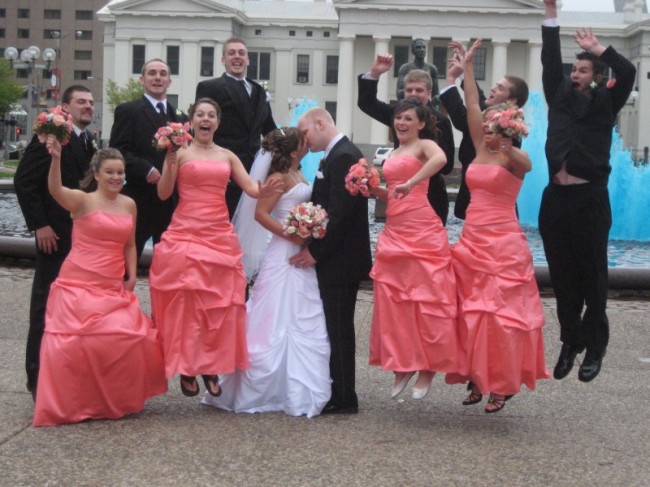 Each bridesmaid is holding a coral colored bridal bouquet that perfectly 
