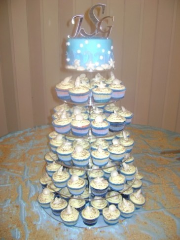 The top tier of this wedding cake is blue with seashell accents and a 