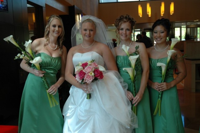 The bridesmaids in their beautiful green bridesmaids dresses hold calla lily