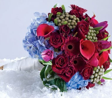 A gorgeous wedding bouquet is filled with red and light blue flowers