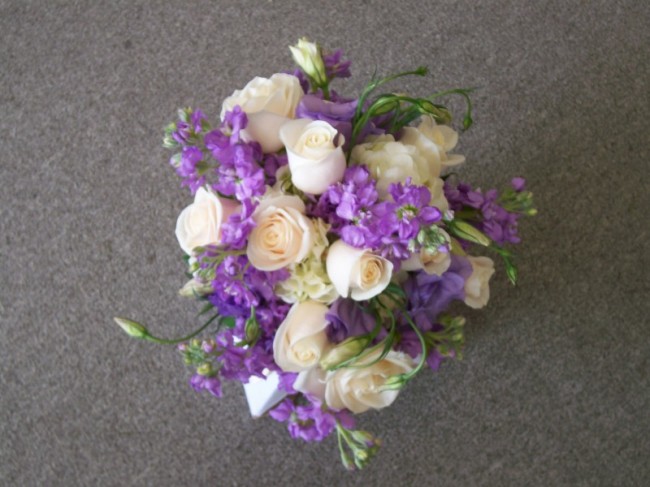A stunning bridal bouquet featured in purple and ivory flowers