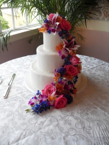  wedding cake creating a brillant floral display in purple orange pink 