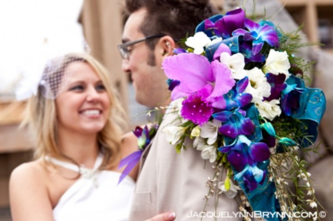 A happy bride holding a radiant blue purple orchid bridal bouquet 