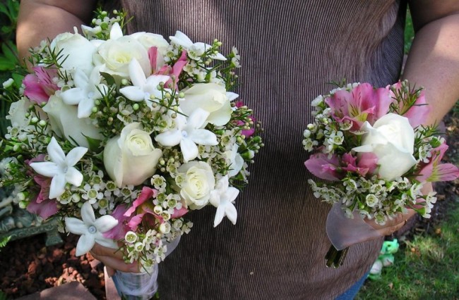 This wedding photo depicts two bridal bouquets decorated with white roses 