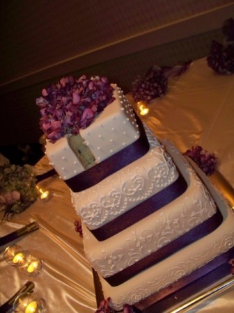 Four tier fondant wedding cake with four royal icing designs purple ribbons