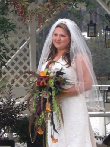 Holding her exotic bridal bouquet containing red yellow and purple flowers 