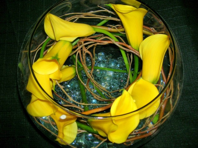 Yellow calla lilies have been wrapped around willow branch and placed upon a