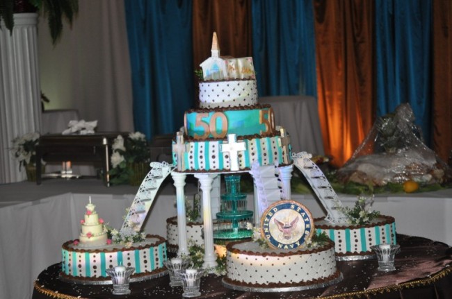 Four cakes in brown teal black and white surround a larger three tier 