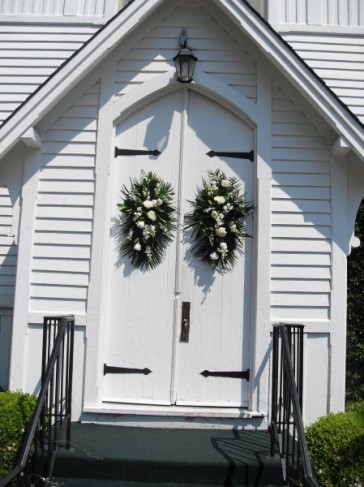 These flower arrangements decorate the church doors before this wedding 