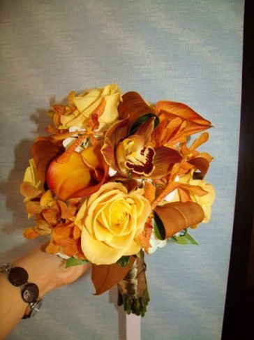 With yellow roses orange lilies and bronze ribbon these wedding flowers 