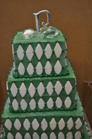 The sides of this birthday cake has a white diamond pattern and green polka