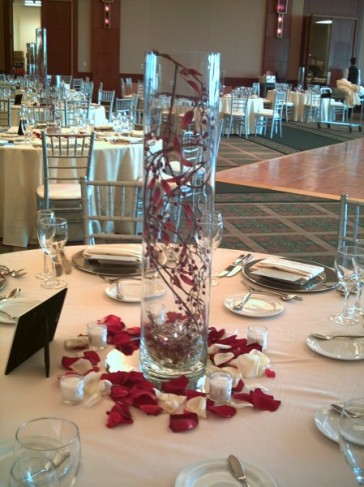 This floral centerpiece has been created using red vines in a tall glass 