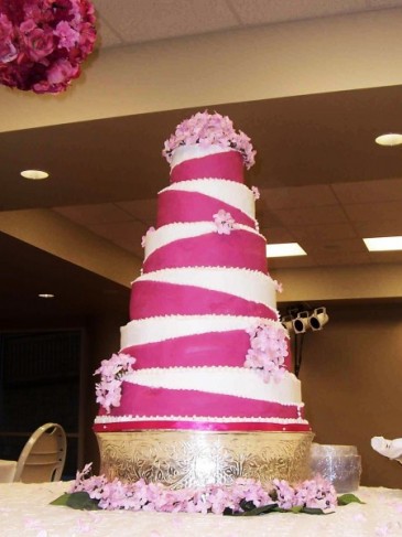 Each tier of this wedding cake has a diagonal hot pink and white design