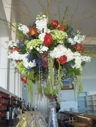 This floral centerpiece has been made using red roses white and blue 