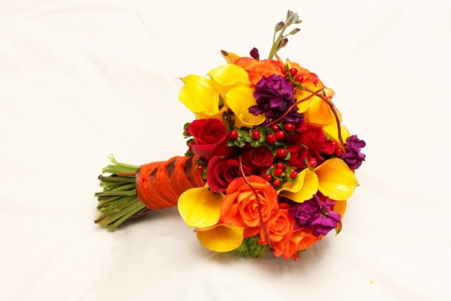 This wedding bouquet features bright flowers in shades of red orange 