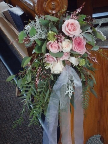 This florist creates a lovely pew decoration out of pink wedding flowers