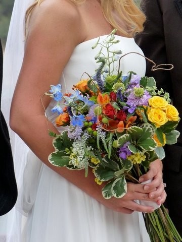 This bride carries a beautiful wedding bouquet featuring yellow purple red