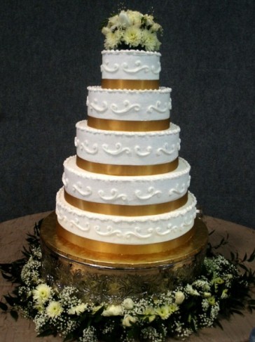 A beautiful wedding cake that features 5 tiers and a lovely accent of gold 