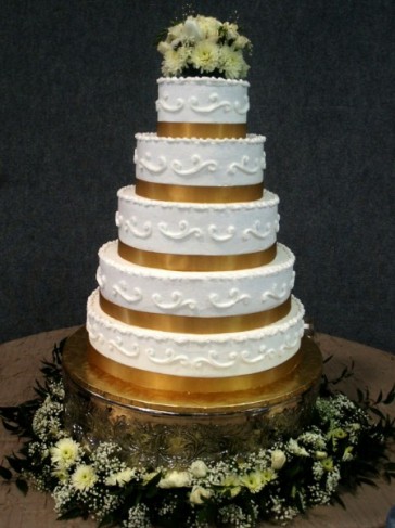 A beautiful wedding cake that features 5 tiers and a lovely accent of gold