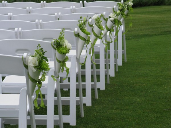 Green and white wedding flowers in cones for an outside ceremony makes for a