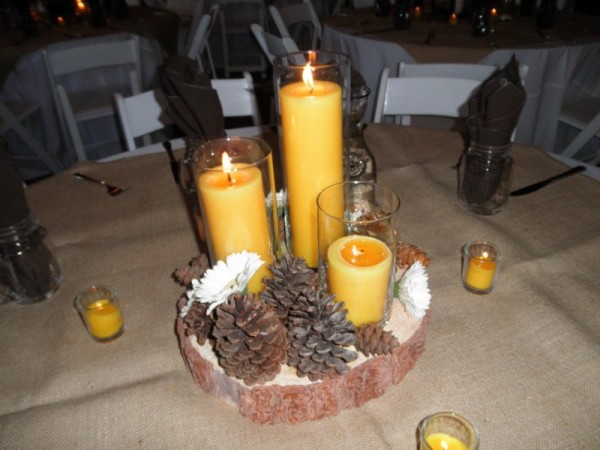 This reception centerpiece features beautiful candles pine cones and white