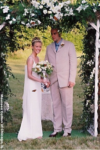 These newlyweds stand happily underneath a wedding ceremony arch decorated