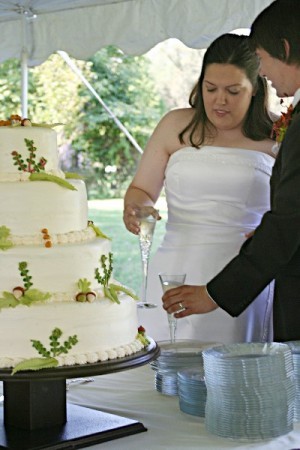 Bride and grown cut the fall wedding cake for presentation at an outdoor 